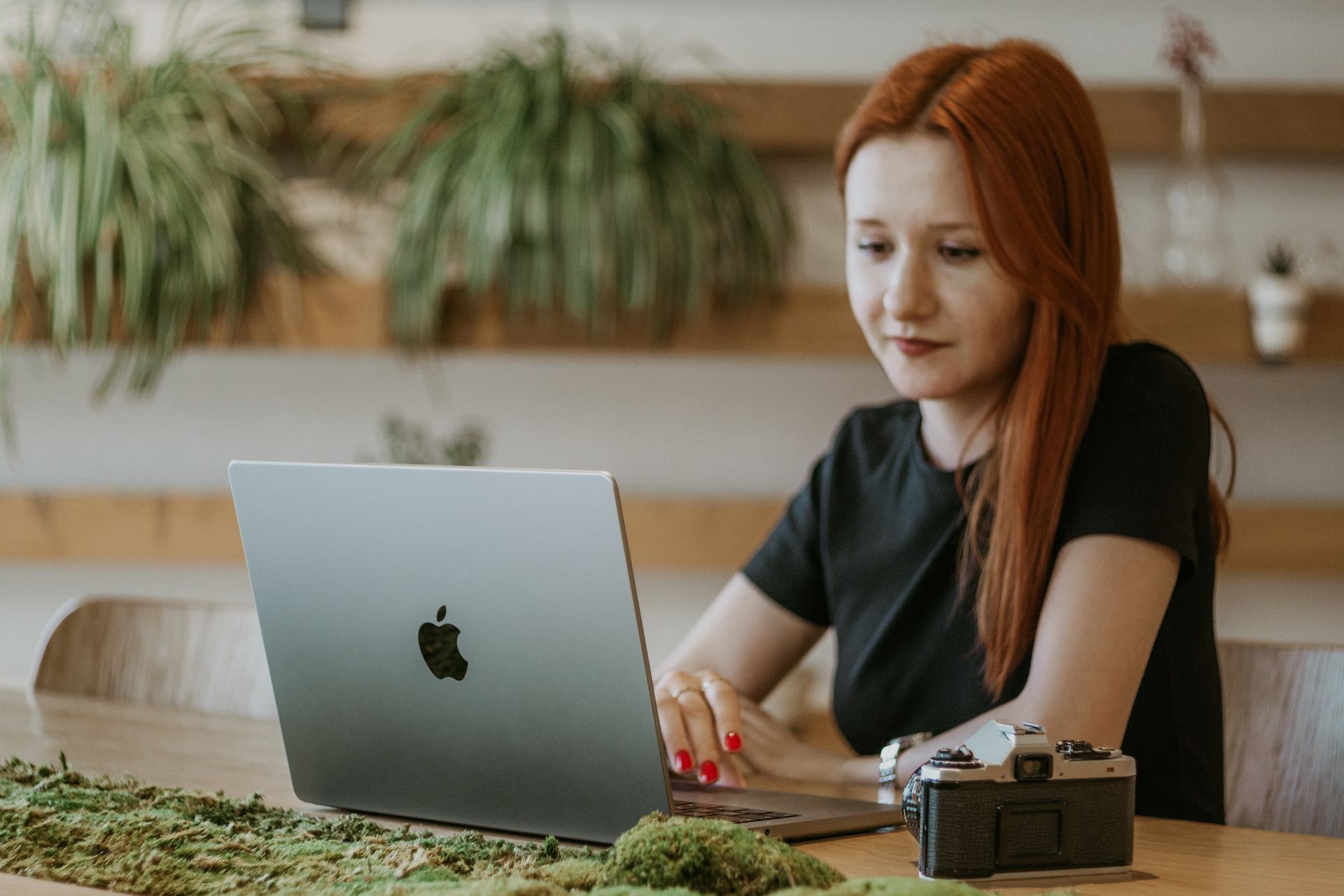 Frau bearbeitet Videos am Laptop neben einer Kamera – Adobe Premiere automatisieren